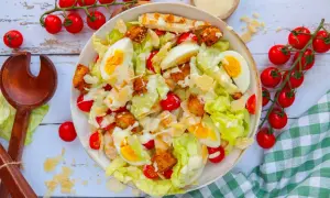 Salade César appétissante : laitue, poulet grillé, œufs durs, tomates cerises, croûtons et copeaux de parmesan. Une recette parfaite pour un repas frais.