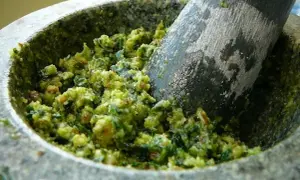 Pilon et mortier remplis d'un pesto vert vif à l'ail des ours, prêt à être dégusté.