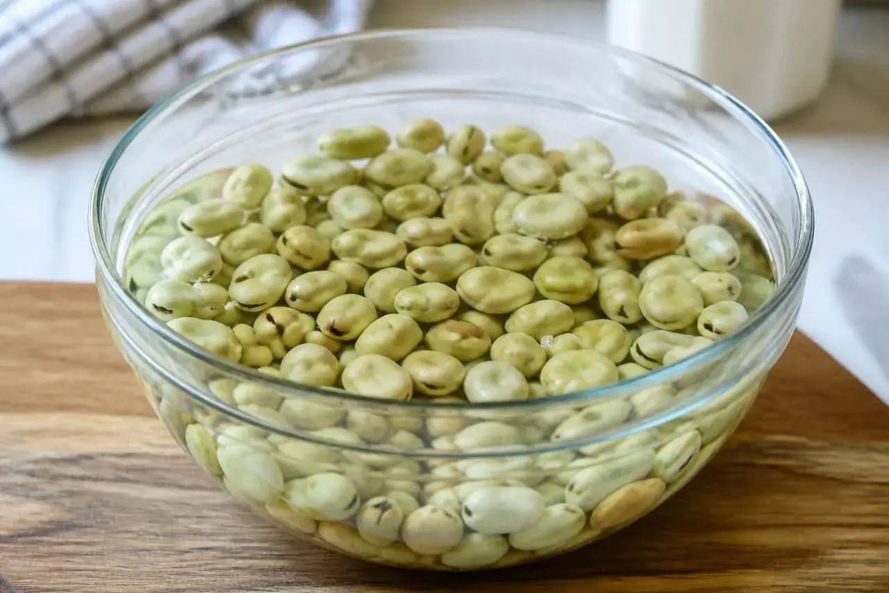 Fèves vertes dans un bol en verre, prêtes pour la cuisson.