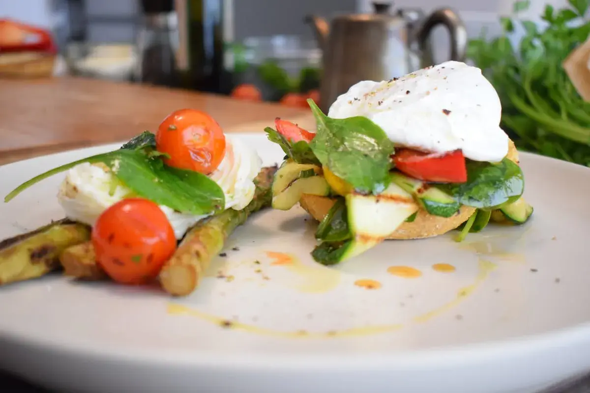 Salade composée printemps : asperges grillées, tomates cerises, œuf poché et légumes croquants sur pain grillé. Un délice frais et coloré.