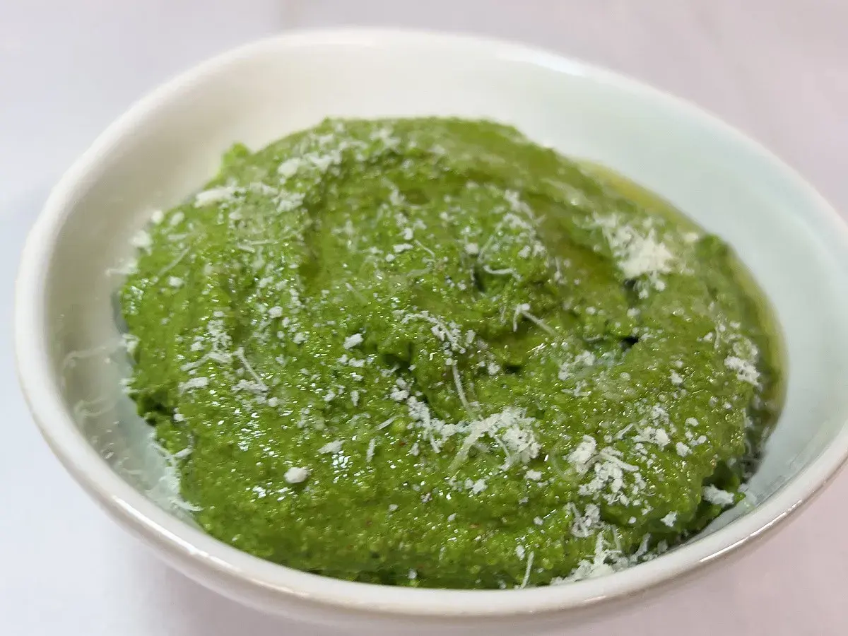 Un bol de pesto épinard frais, parsemé de copeaux de parmesan. Une touche de vert vibrant pour rehausser vos plats.