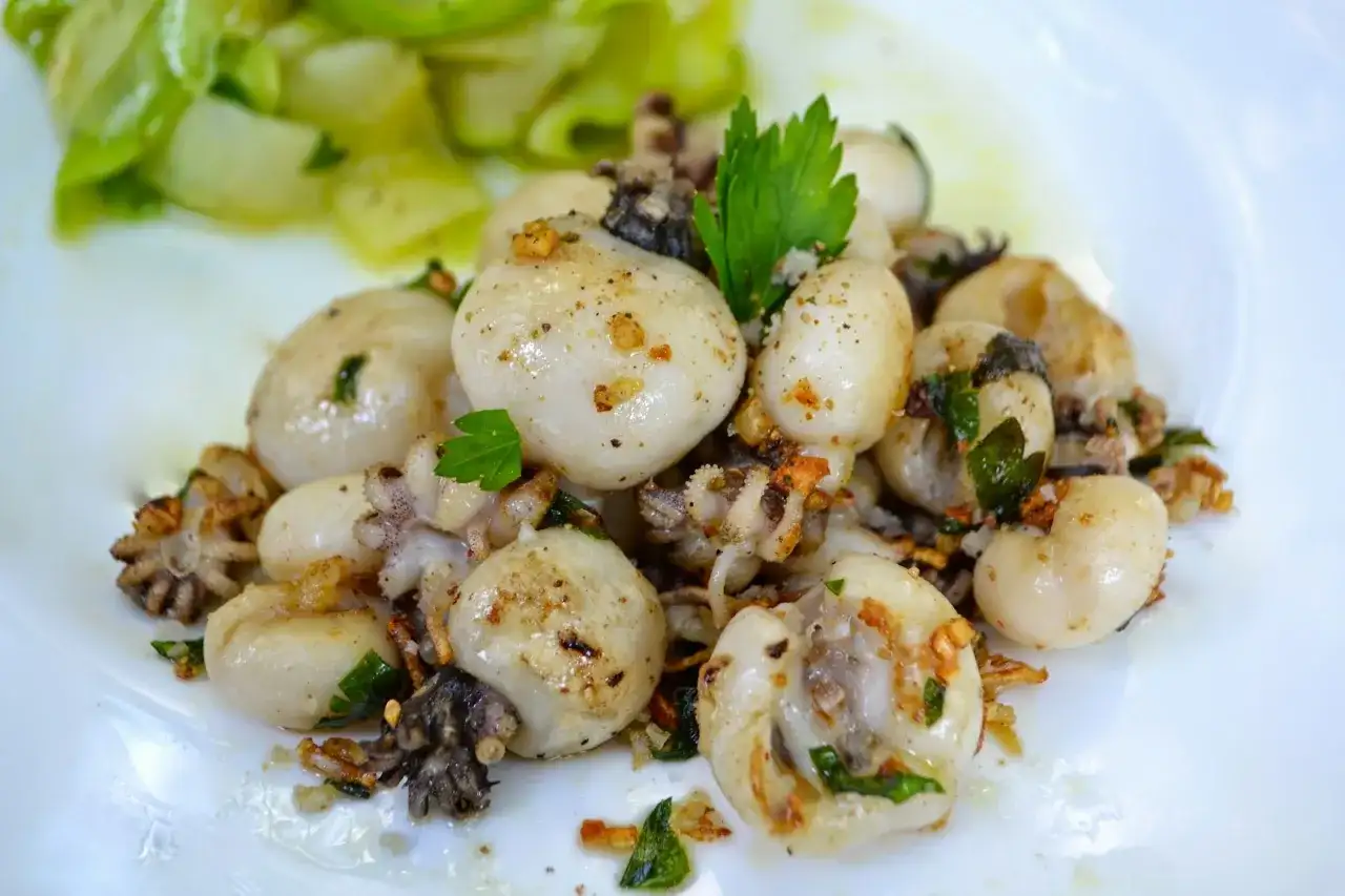 Chipiron a la plancha, tendres et savoureux, parsemés d'ail et de persil, accompagnés de légumes verts croquants.