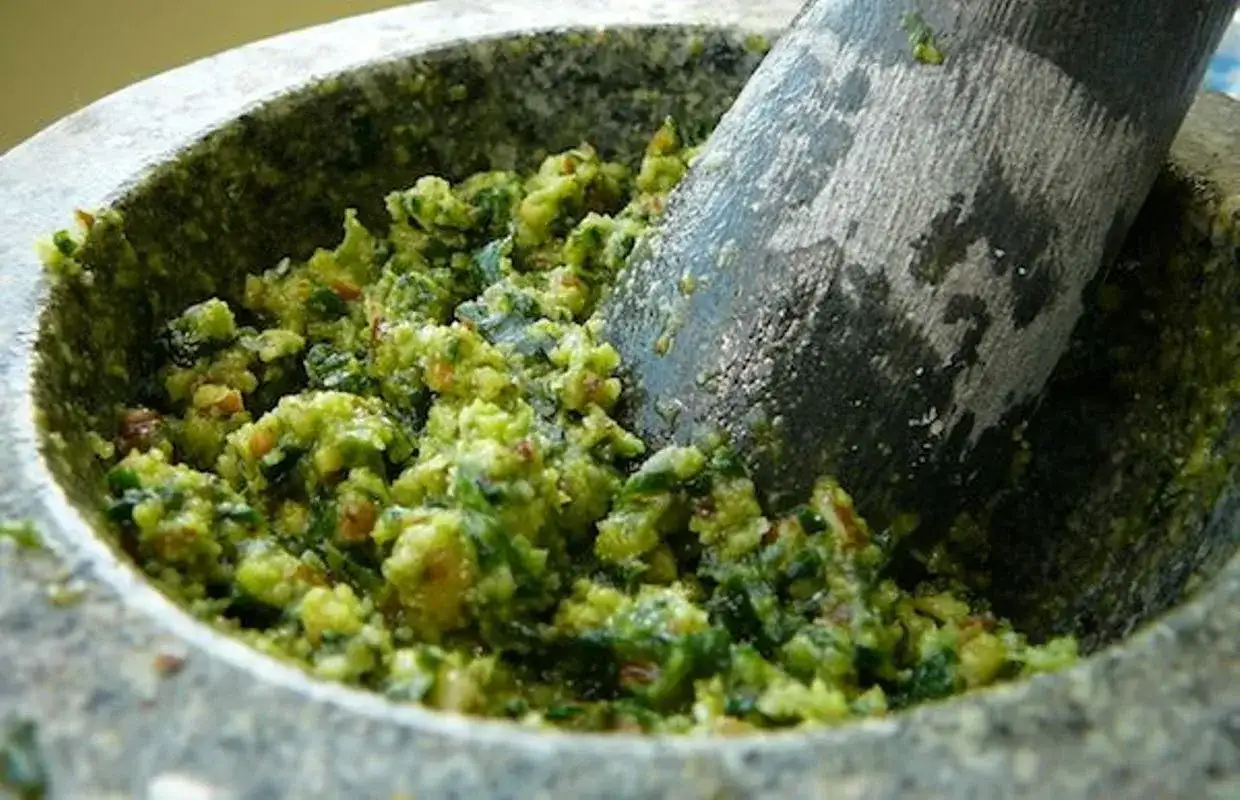 Pilon et mortier remplis d'un pesto vert vif à l'ail des ours, prêt à être dégusté.
