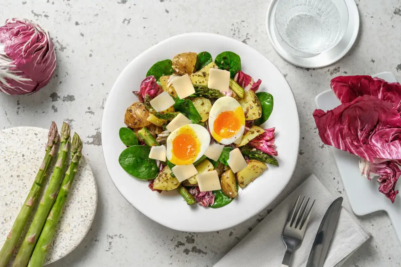 Une délicieuse salade composée printemps avec œufs mollets, pommes de terre rôties, asperges, fromage et radicchio.