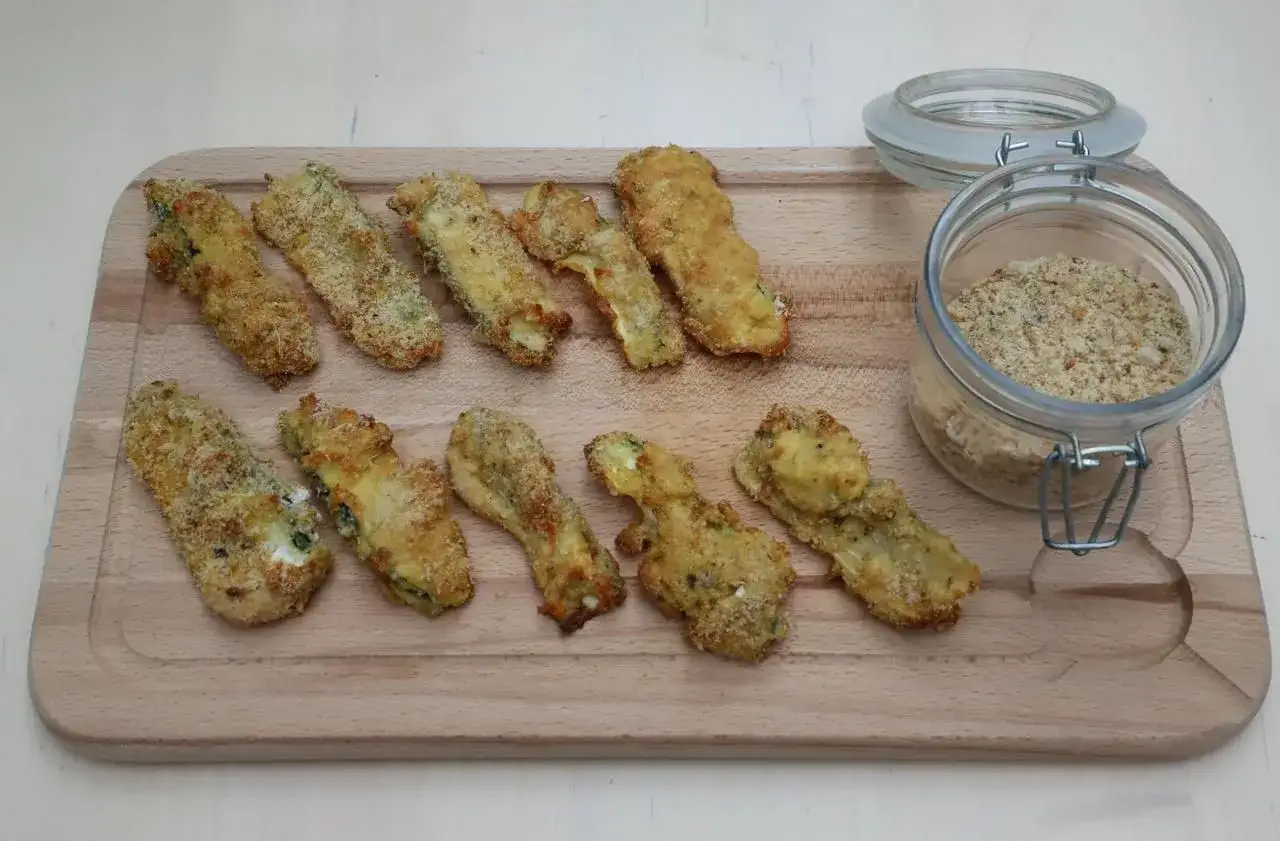 Bâtonnets de courgettes panés, dorés et croustillants, prêts à être dégustés avec de la chapelure maison.