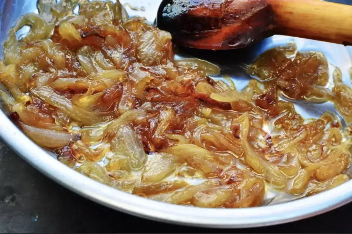 Oignons caramélisés dorés et fondants dans une poêle, prêts à sublimer un plat.