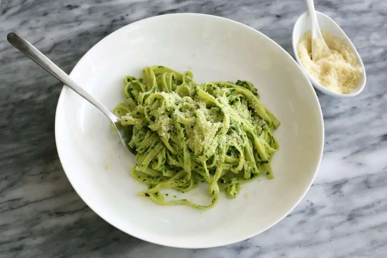 Assiette de pâtes fraîches nappées d'un pesto épinard maison, saupoudrées de parmesan râpé. Un délice vert et savoureux.