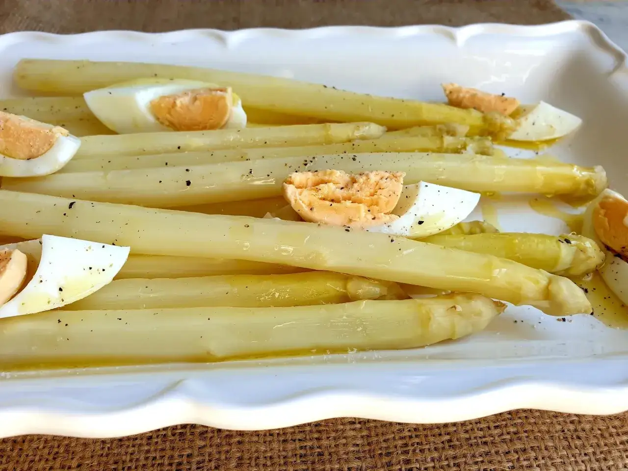 Asperges blanches tendres, parfaitement cuites, arrosées d'une vinaigrette légère et parsemées d'œufs durs. Un délice printanier.