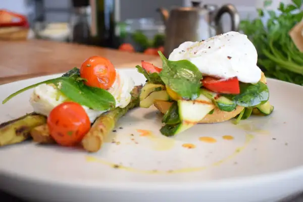 Salade composée printemps : asperges grillées, tomates cerises, œuf poché et légumes croquants sur pain grillé. Un délice frais et coloré.