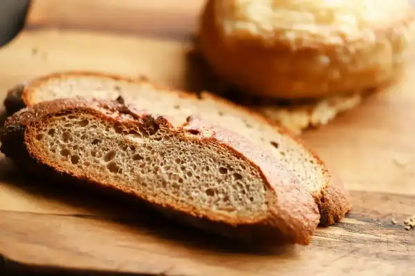 Tranches de pain artisanal sur planche en bois, parfaites pour faire de la chapelure maison.
